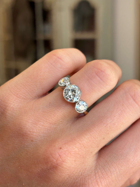 Antique Edwardian old-cut diamond three-stone engagement ring featuring three old-cut diamonds in a timeless trilogy design, worn on a hand.
