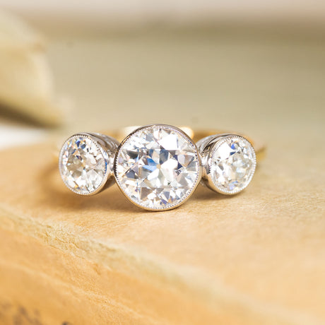 Antique Edwardian old-cut diamond three-stone ring featuring a larger central old-cut diamond flanked by two matching diamonds.