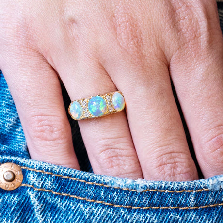 Antique Edwardian opal and diamond three-stone ring styled with denim pocket.