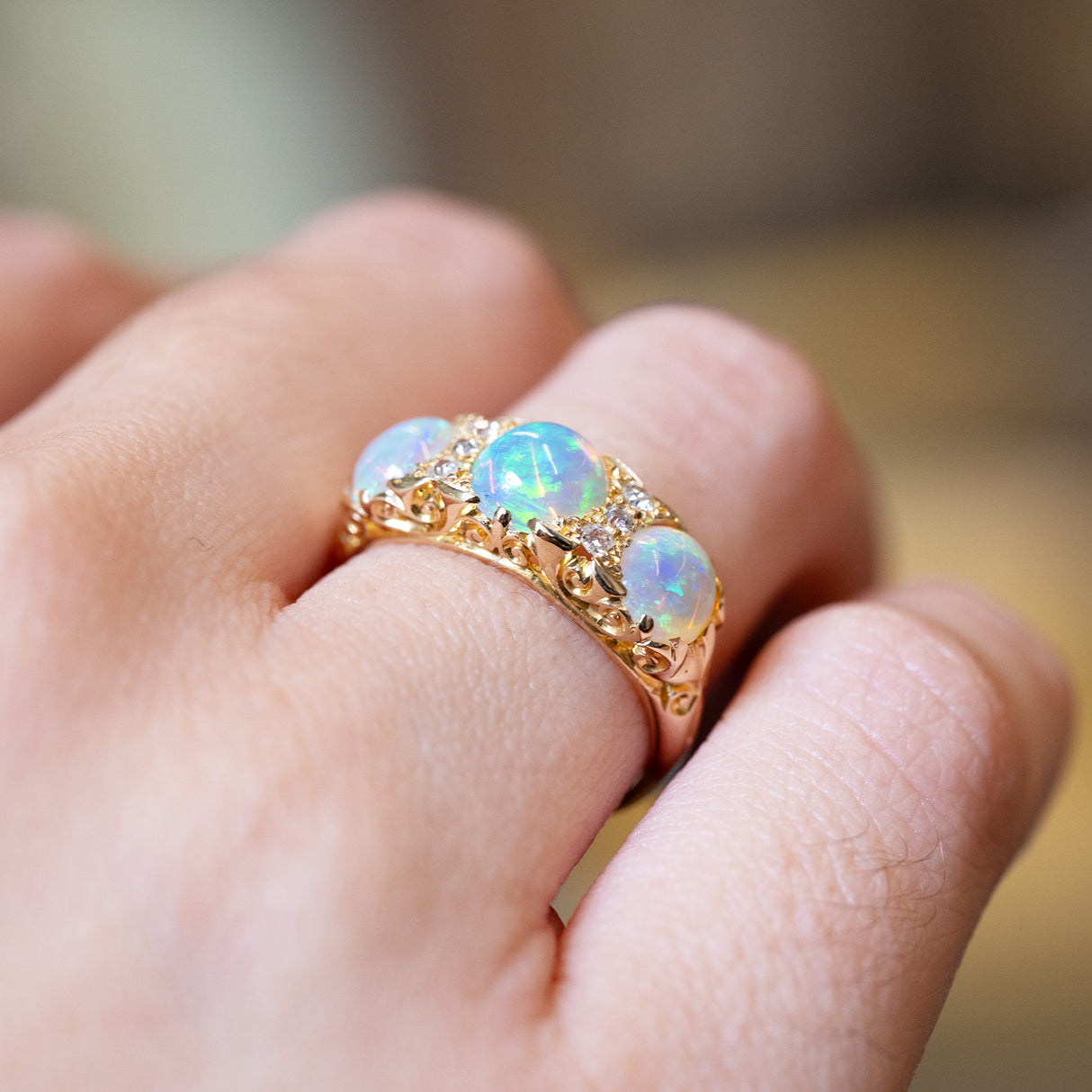 Antique Edwardian opal and diamond three-stone ring showing ornate elevated gold setting.