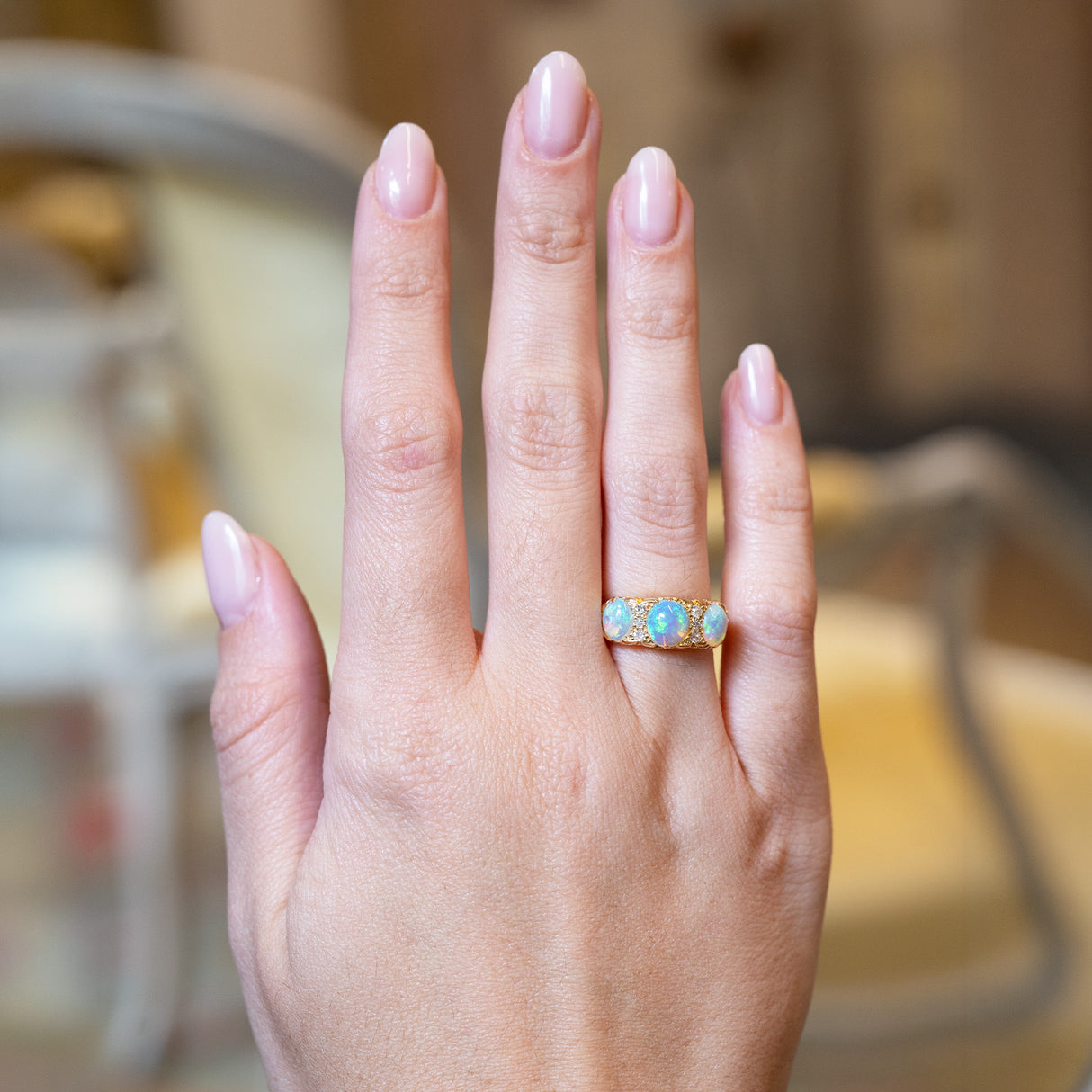 Antique Edwardian opal and diamond three-stone ring worn on hand.