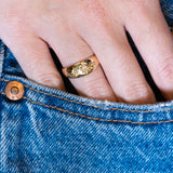 Antique Edwardian three-stone diamond gypsy ring worn with hand resting in denim pocket.
