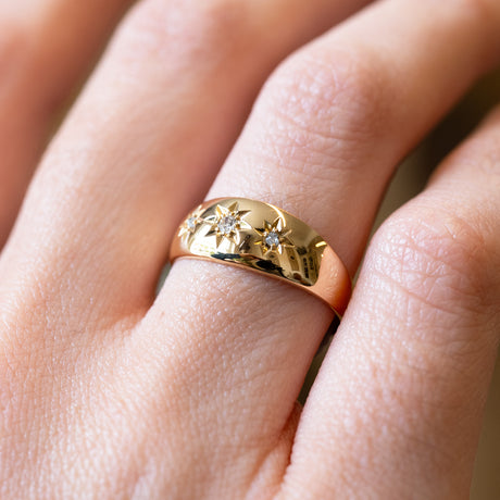Detailed view of antique Edwardian three-stone diamond gypsy ring with polished gold band.