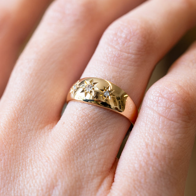 Detailed view of antique Edwardian three-stone diamond gypsy ring with polished gold band.
