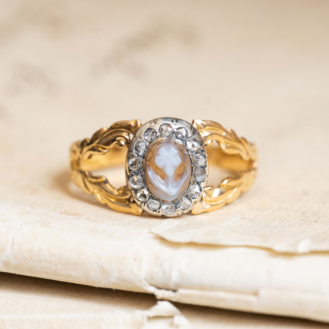 Antique Georgian forget-me-not cluster ring featuring a carved cameo centre framed by diamonds in ornate yellow gold.