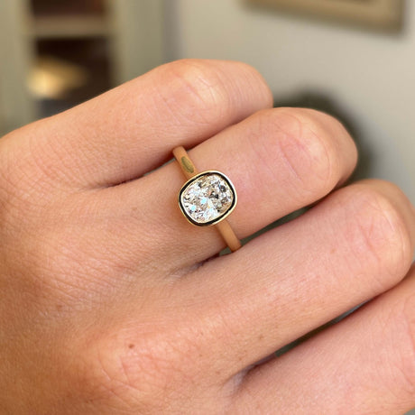 Antique-inspired cushion old-cut diamond solitaire engagement ring with a sparkling cushion old-cut diamond in a refined rub-over yellow gold setting