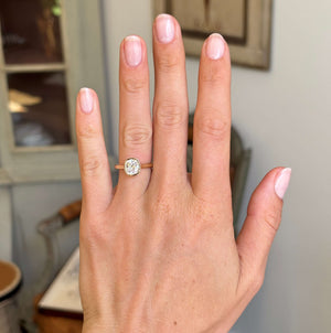 Antique-inspired cushion old-cut diamond solitaire engagement ring worn on hand showcasing its classic heirloom-inspired design