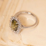 Antique-inspired green sapphire and diamond cluster engagement ring with a cushion-cut green sapphire and diamond halo setting in white gold.