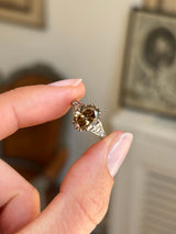 Antique-inspired hazelnut-brown diamond and rose-cut diamond engagement ring featuring a hazelnut-brown diamond centre stone with rose-cut diamond accents, held by hand.
