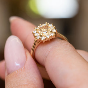 Antique inspired primrose-yellow sapphire and diamond cluster engagement ring highlighting the oval yellow sapphire and surrounding diamond cluster in yellow gold.
