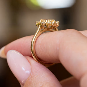 Antique inspired primrose-yellow sapphire and diamond cluster engagement ring featuring an oval primrose-yellow sapphire surrounded by a brilliant-cut diamond halo.
