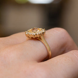 Antique inspired primrose-yellow sapphire and diamond cluster engagement ring highlighting the elevated diamond halo setting and yellow gold band.