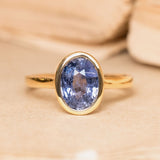 Antique-inspired slate blue sapphire solitaire engagement ring featuring an oval-cut slate blue sapphire in a smooth yellow gold rub-over setting.