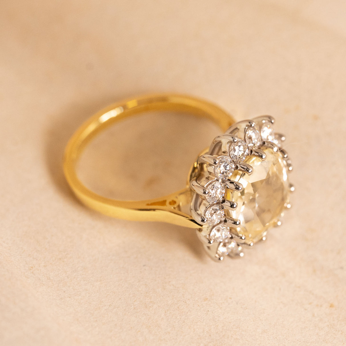 Antique inspired yellow Ceylon sapphire and diamond cluster engagement ring showing the elevated diamond cluster setting and yellow gold band.