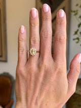 Antique-inspired yellow sapphire and diamond cluster engagement ring with an oval yellow sapphire centre stone and diamond halo, displayed on a hand.