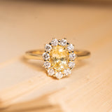 Antique-inspired engagement ring featuring a golden yellow sapphire surrounded by a sparkling diamond cluster in yellow gold.