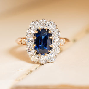 Antique Jugendstil ring featuring a royal-blue sapphire surrounded by a cluster of old-cut diamonds in a gold setting.