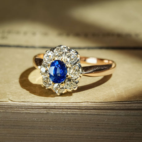 Antique Belle Époque sapphire ring with oval blue gemstone and diamond cluster setting