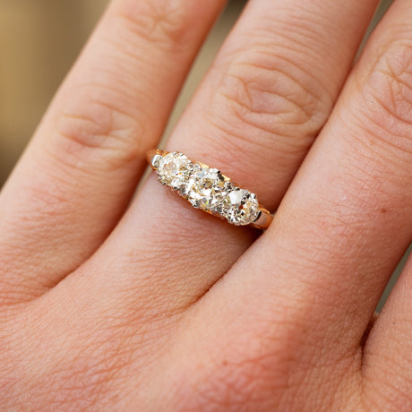 An antique ring with three diamonds on a person's finger.