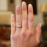 Hand wearing a victorian diamond three stone ring with a blurred background.