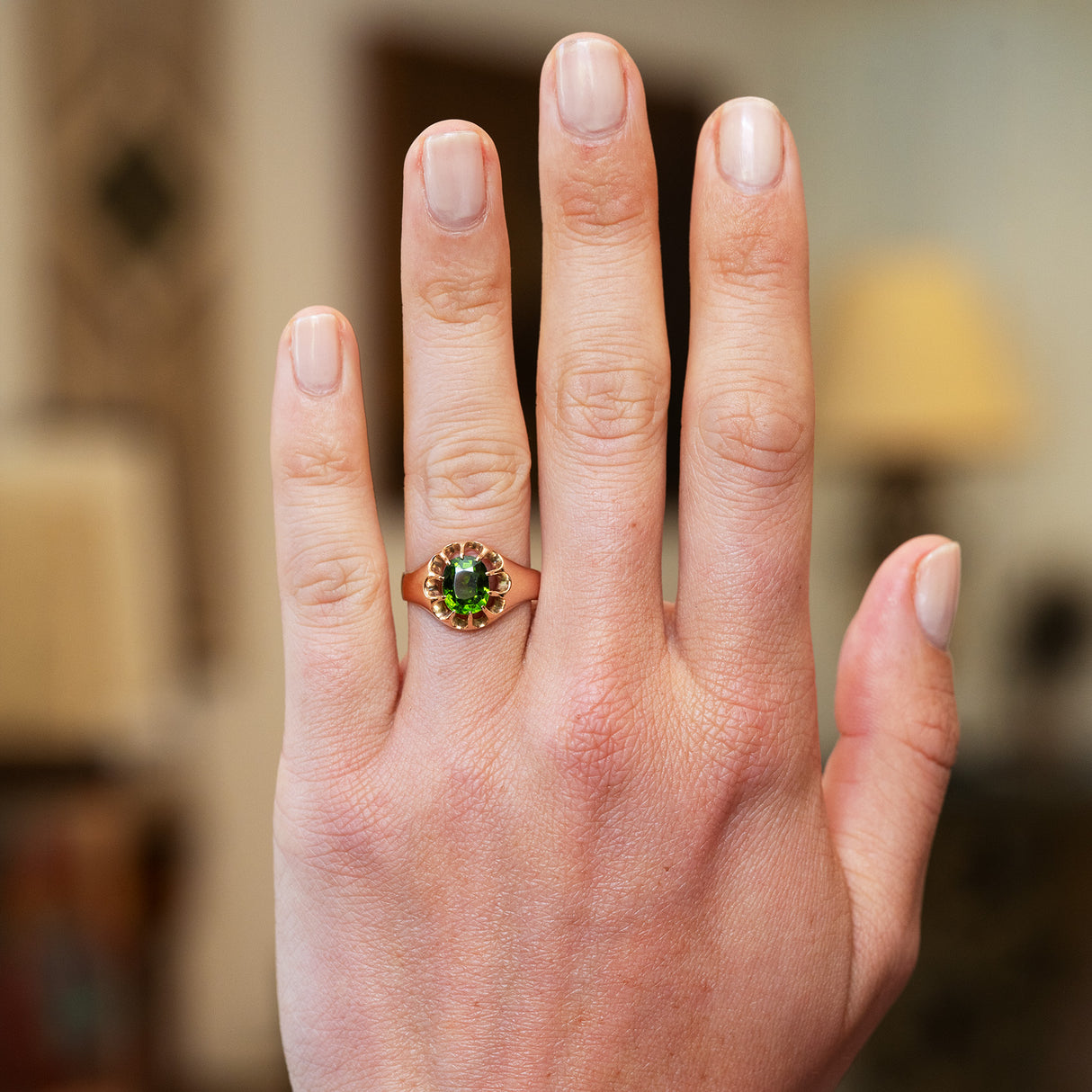 Green zircon ring worn on hand with natural manicure.