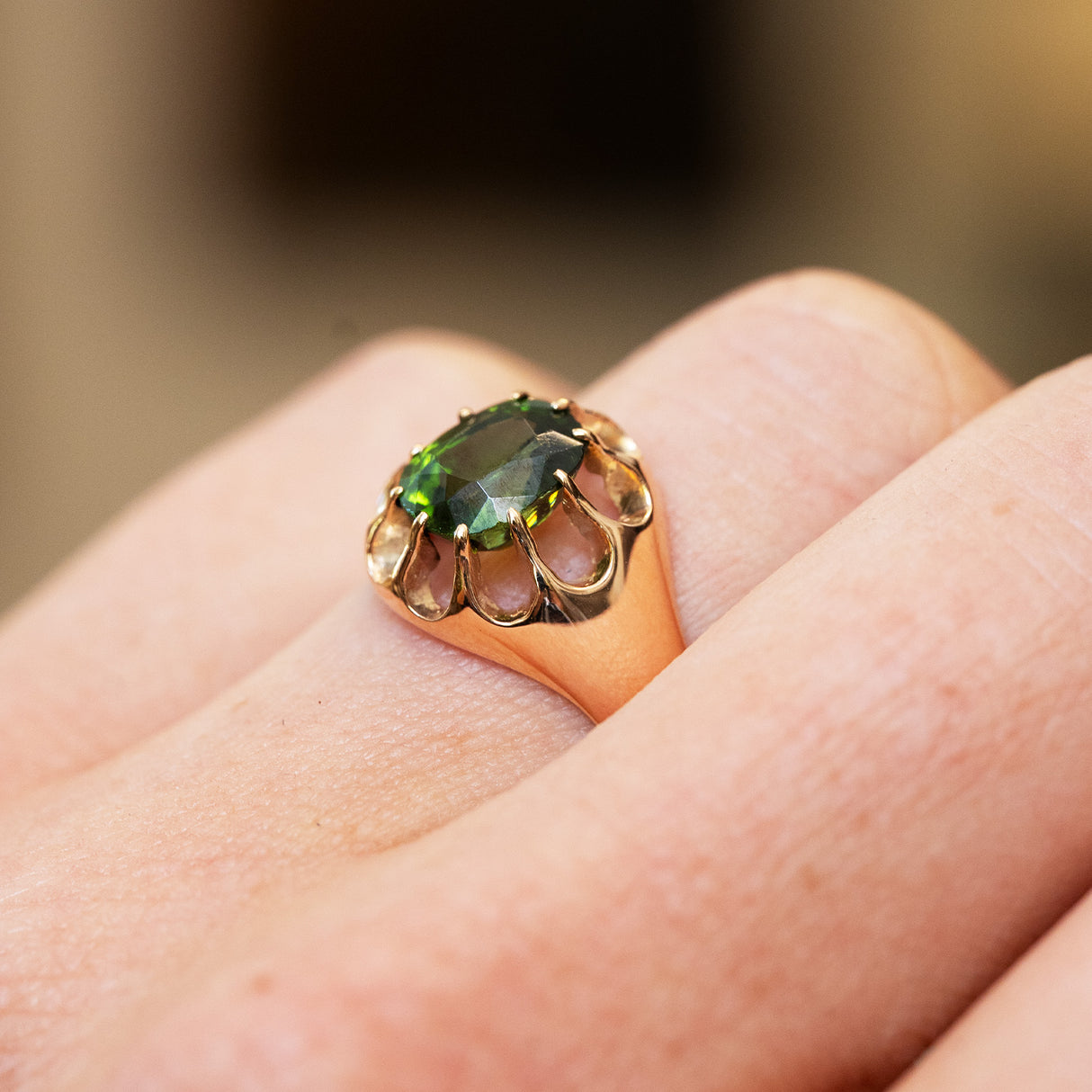 Green gemstone ring showing open gold setting in an antique design.