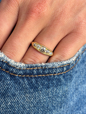 Antique Victorian old-mine cut diamond five-stone engagement ring set with five graduated old-mine cut diamonds, worn on a hand.