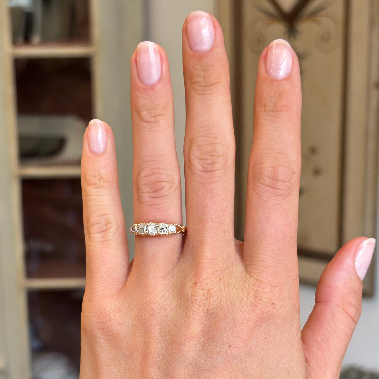 Antique Victorian old-mine diamond five-stone ring set with five graduated old-mine cut diamonds, displayed on a hand.