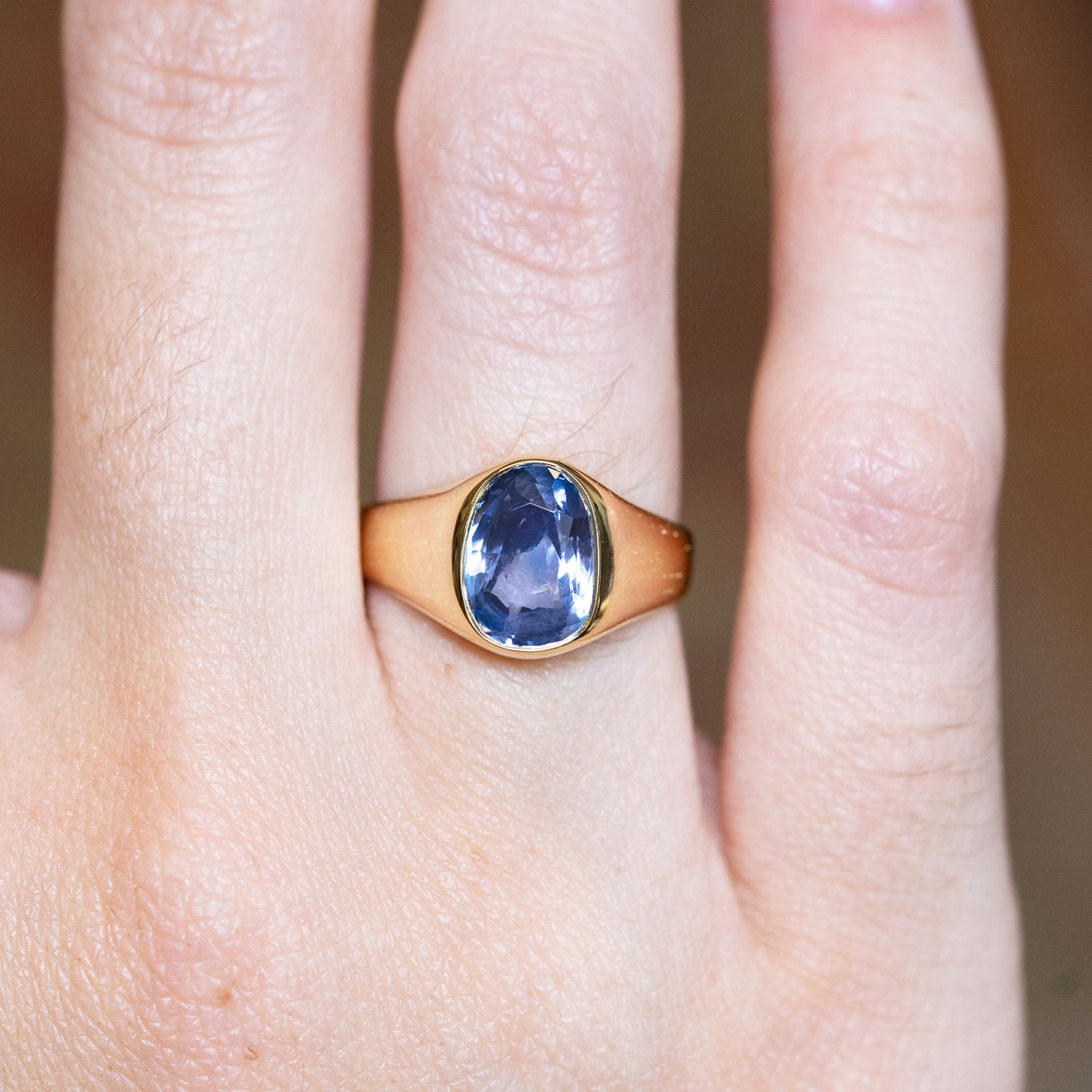 Antique Victorian sapphire single-stone ring with oval blue sapphire shown on finger.