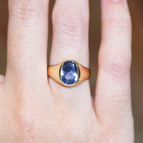 Antique Victorian sapphire single-stone ring with oval blue sapphire shown on finger.