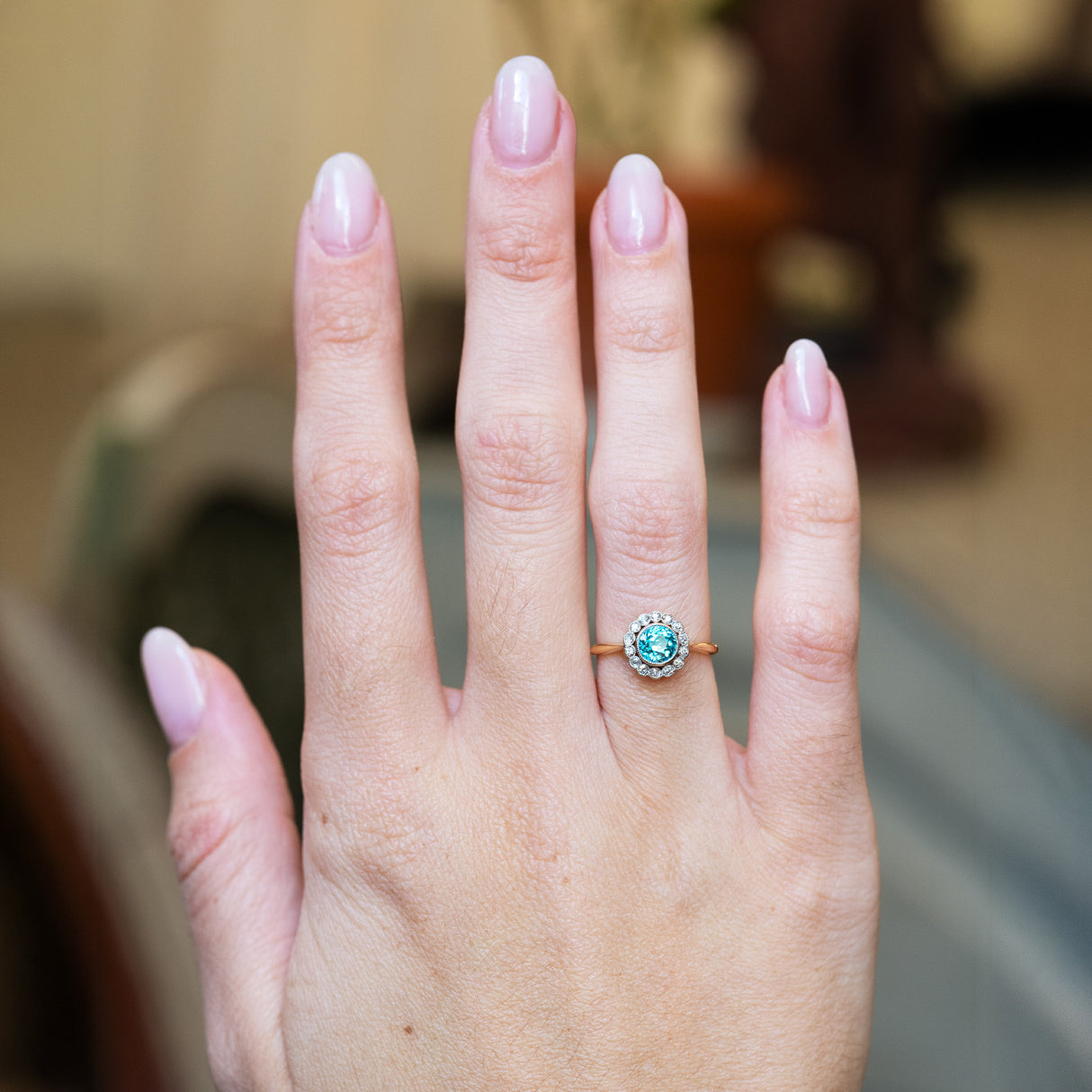 Antique cluster ring worn on hand with vivid blue zircon and diamond surround.