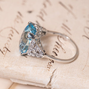 Art Deco aquamarine and diamond statement ring showcasing an emerald-cut aquamarine with openwork diamond shoulders and platinum setting.