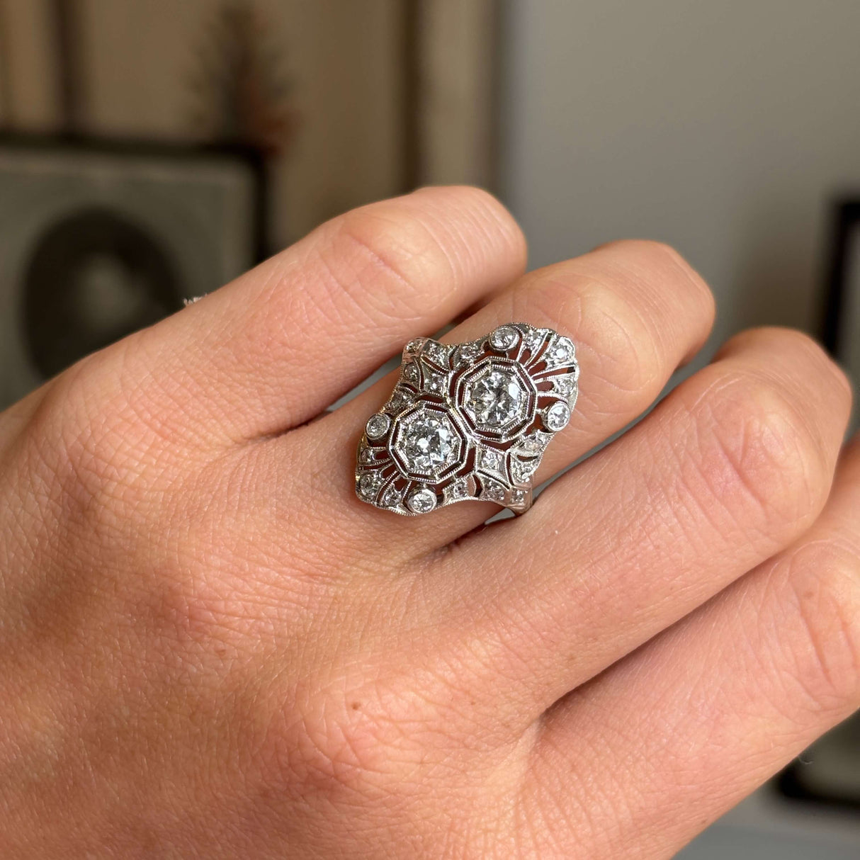 Close-up of an antique Art Deco platinum cocktail ring featuring intricate filigree metalwork and a dazzling diamond cluster, highlighting exceptional craftsmanship and geometric design.