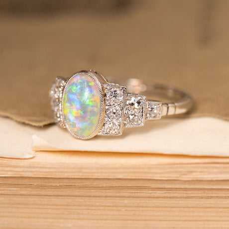 Antique Art Deco opal and diamond ring showcasing an oval opal, accented by old-cut diamonds and fine milgrain detailing.