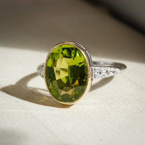 Art Deco peridot ring featuring oval green gemstone and diamond shoulders