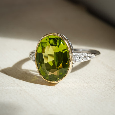 Art Deco peridot ring featuring oval green gemstone and diamond shoulders
