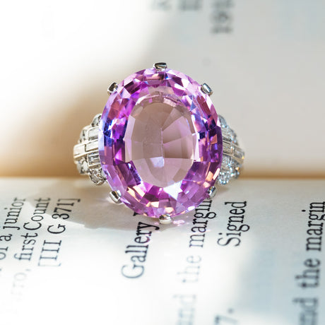 Art Deco pink topaz and diamond cocktail ring with large oval pink topaz and surrounding diamond accents.