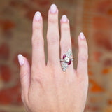 Art nouveau diamond and ruby cocktail ring worn on hand with sculptural design.