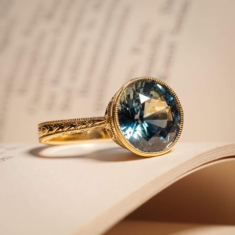 Blue green sapphire solitaire engagement ring with carved gold setting
