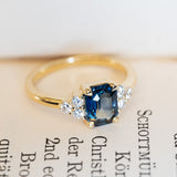 blue sapphire three stone ring with diamonds in yellow gold