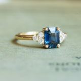emerald cut blue sapphire ring with diamond sides in yellow gold