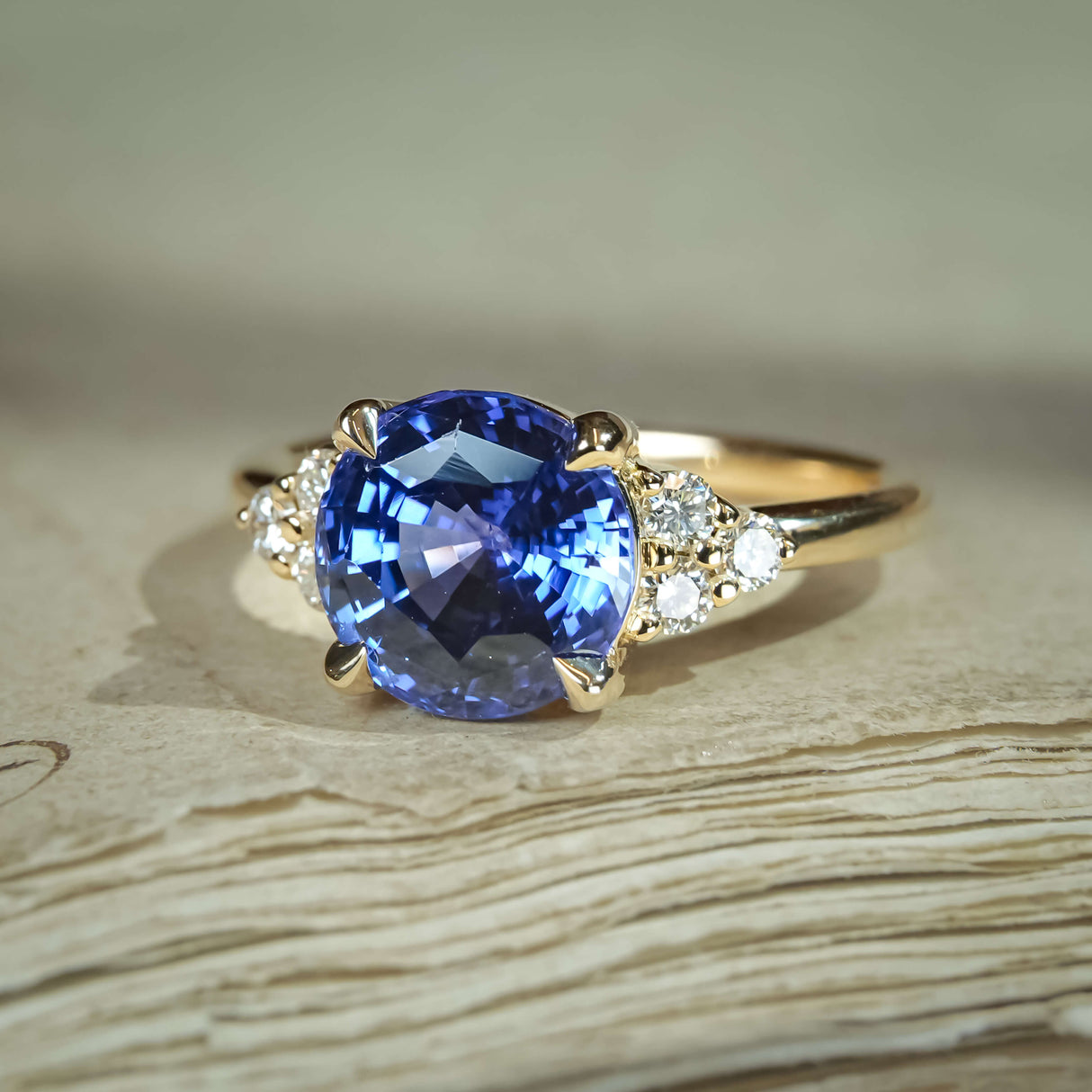 Blue sapphire engagement ring featuring round centre and trefoil diamond cluster shoulders