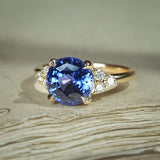 Blue sapphire engagement ring featuring round centre and trefoil diamond cluster shoulders
