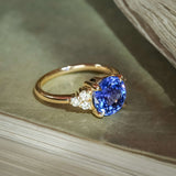 Round blue sapphire ring with diamond trefoil accents in a classic gold setting
