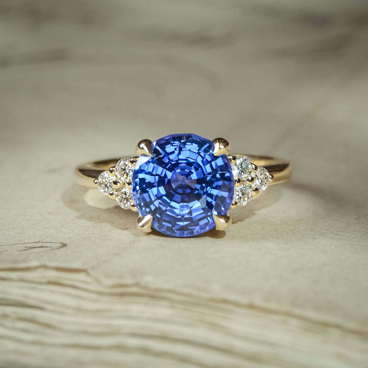Round blue sapphire with diamond cluster trefoil shoulders in classic setting