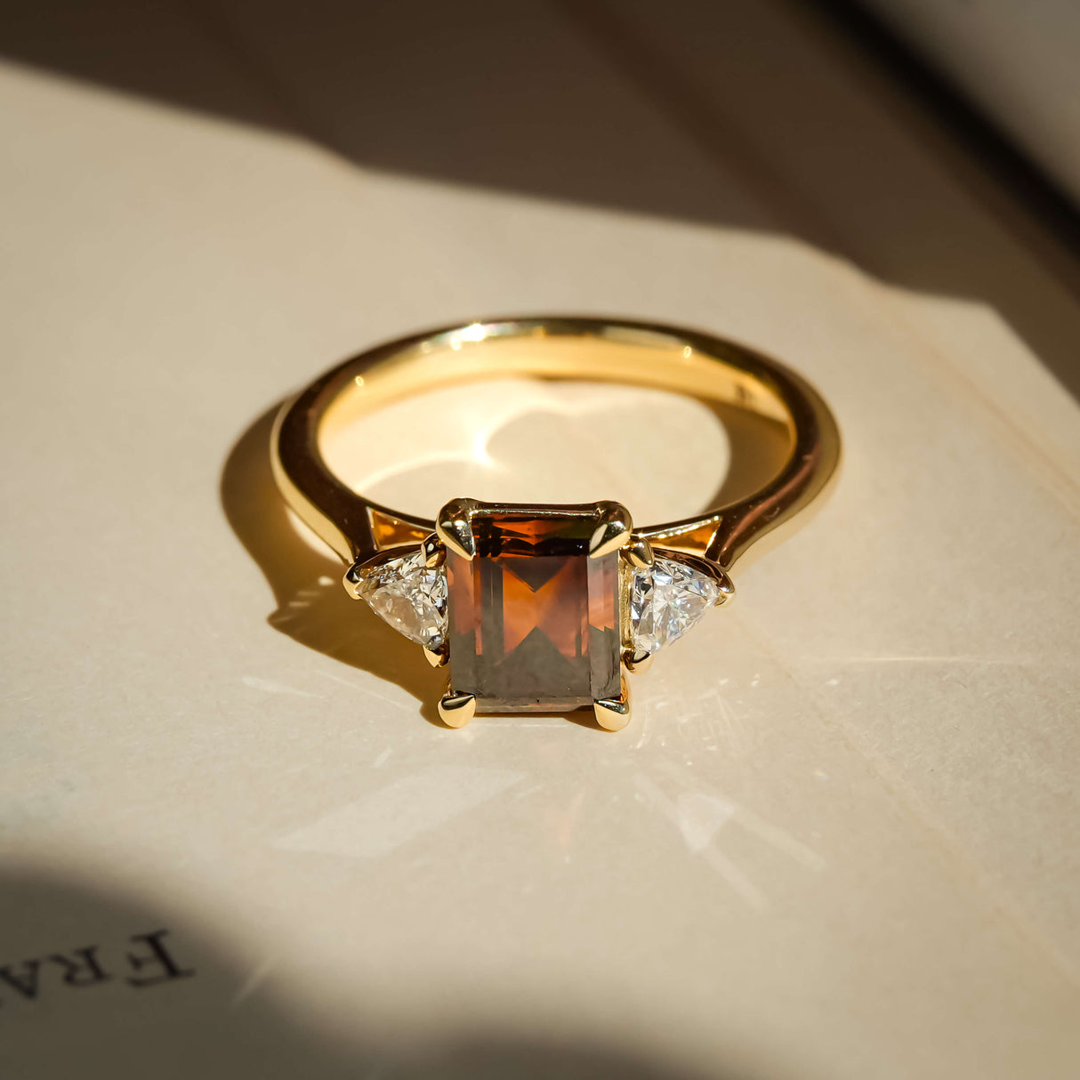 brown diamond three stone engagement ring with yellow gold band and diamond accents