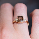 Chocolate brown diamond cluster tre-foil engagement ring worn on finger with diamond side stones.