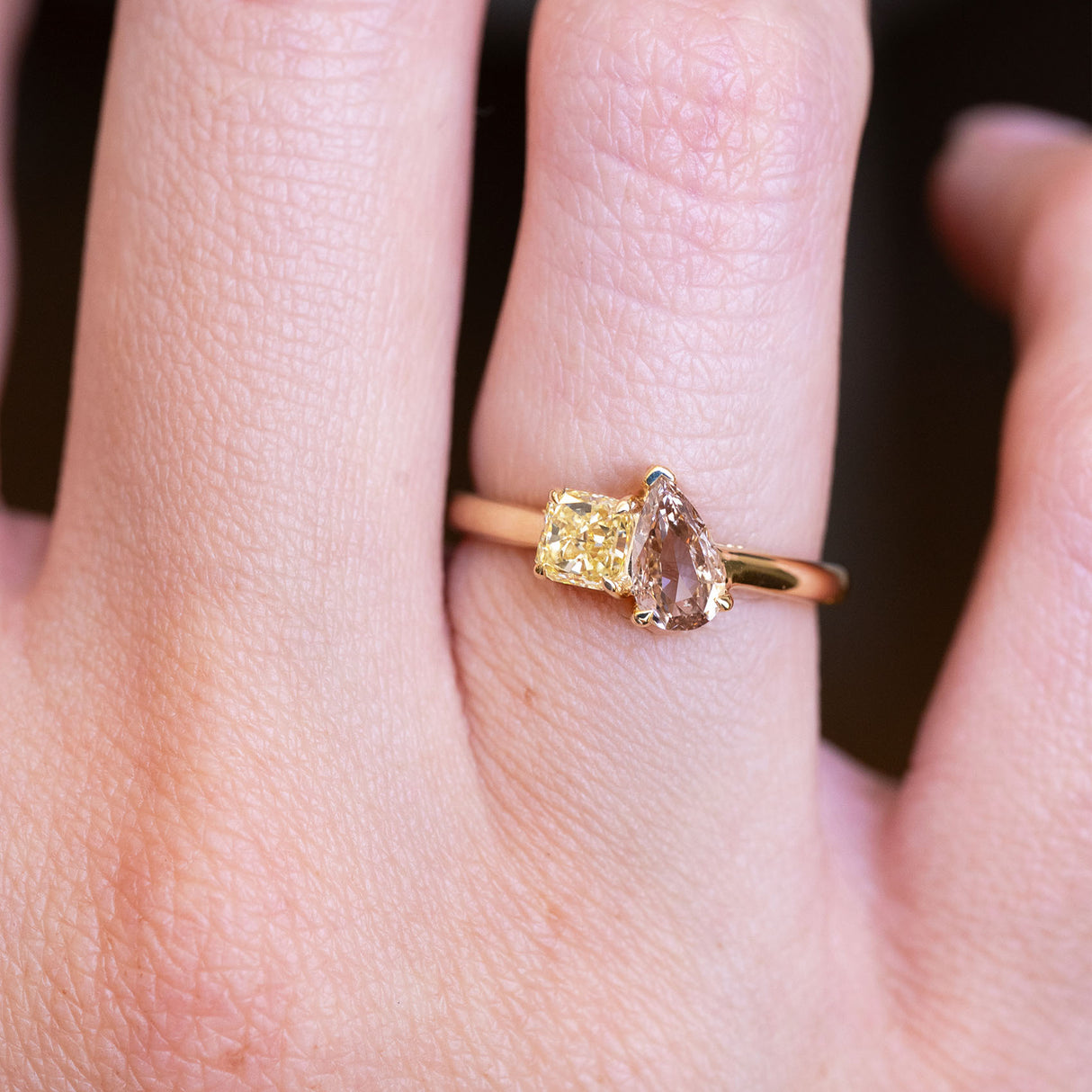 Brown and yellow diamond Toi et Moi engagement ring worn on finger with mixed diamond pairing.