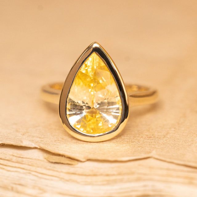 Canary yellow pear-cut sapphire solitaire ring featuring a vibrant yellow sapphire set in polished yellow gold.