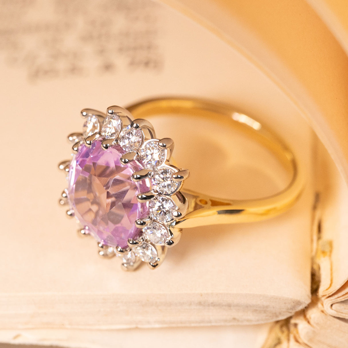 Pink sapphire and diamond halo ring with a natural Ceylon sapphire framed by bright white diamonds in a classic gold setting.
